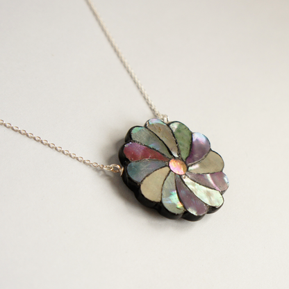 ‘Banka’ is a lacquered mother-of-pearl (Raden) necklace reinterpreted with a contemporary sensibility. Inspired by the classical ‘twisted chrysanthemum’ motif, each piece has been meticulously crafted by Kaori Sugano.
Within a small circle measuring approximately 3 centimetres in diameter, natural mother-of-pearl in varying hues is arranged petal by petal. The chain is made of 925 sterling silver.